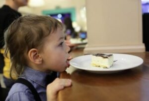 ребенок заглядывает в тарелку на столе
