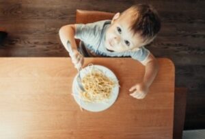 ребенок ест макароны из тарелки