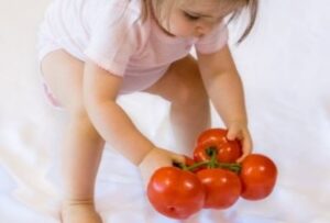 ребенок берет в руки помидоры