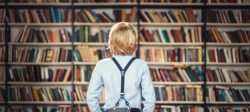 мальчик в библиотеке с книжными полками