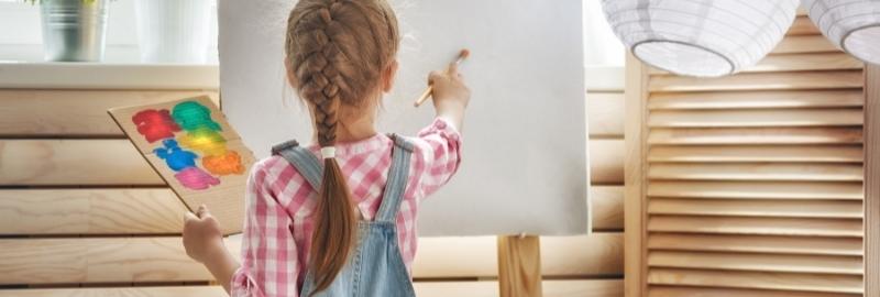 девочка рисует на мольберте 