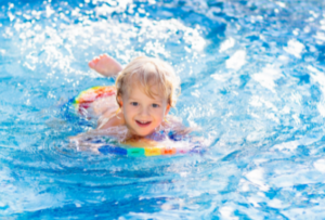 девочка в бассейне плывет при поддержке спецсредств